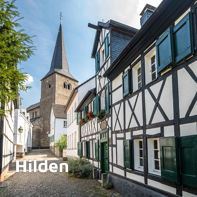 Straßenzug mit altem Fachwerkhaus und der Reformationskirche zu Hilden im Hintergrund