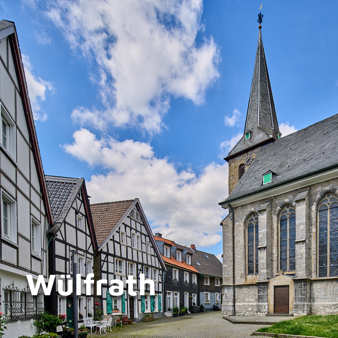 Die Innenstadt Wülfraths mit Fachwerkhäusern links und Seitenansicht der Kirche rechts.
