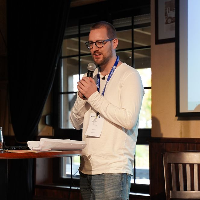 Ein Mann trägt einen lustigen Poetry Slam auf einer Bühne vor. 