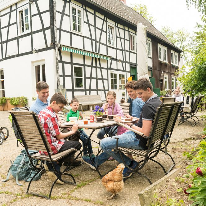 Familie sitzt am Tisch bei Kaffee und Kuchen auf der Terrasse des Hofcafes vom Hof zur Hellen in Velbert-Neviges