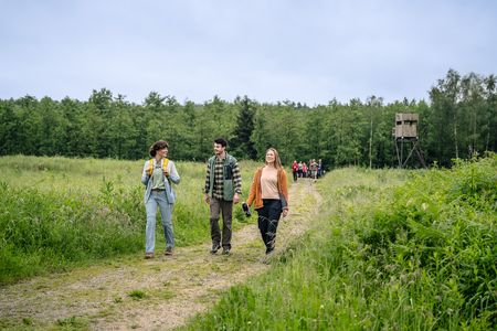 Drei Wandernde wandern fröhlich auf einem Feldweg