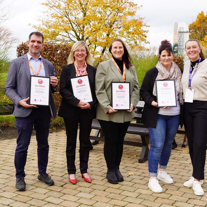 Auf dem Bild sind 5 Personen zu sehen, 4 Personen halten die Zertifizierung als neanderland STEIG Qualitätsbetrieb in den Händen. 