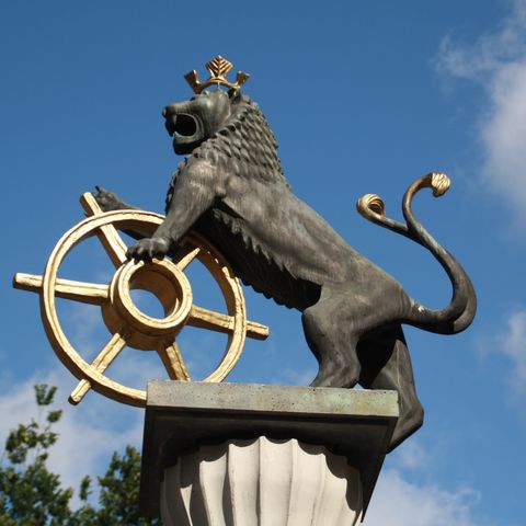 Lion sculpture with a golden wheel and a golden crown on the fountain at the market square in Ratingen