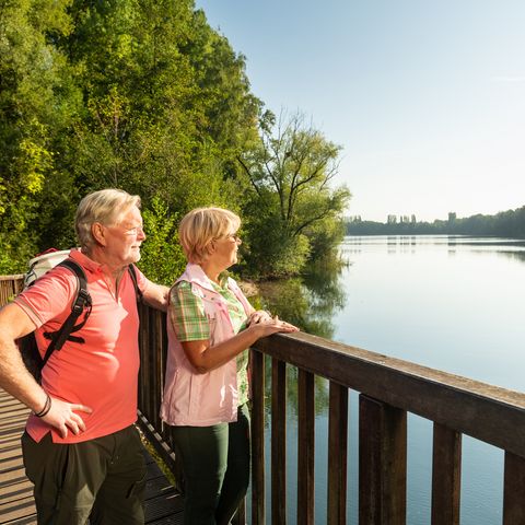 Donna e uomo stanno su un ponte e guardano il Menzelsee a Hilden am neanderland STEIG