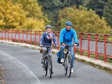 Zwei Fahrradfahrer fahren über das Viadukt Ruhrstraße Süd auf dem PanoramaRadweg niederbergbahn