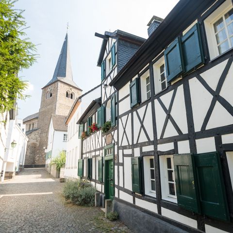 Straat met een oud vakwerkhuis en de Reformatiekerk in Hilden op de achtergrond