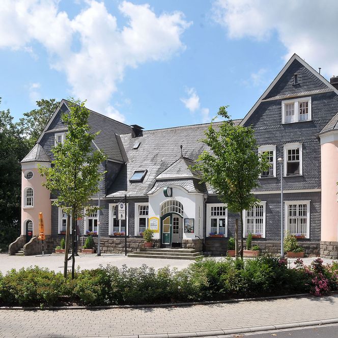 altes Bahnhofsgebäude in Haan mit Beet und drei kleinen Bäumen im Vordergrund