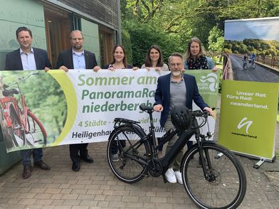 Photo de presse avec des représentants de la ville, des affiches et un vélo sur la piste cyclable panoramique Niederbergbahn