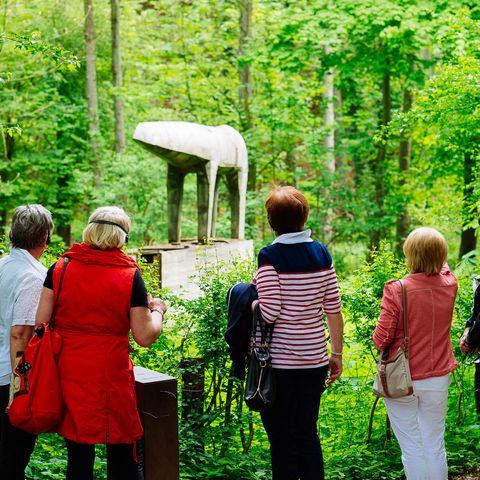 Five women stand with their backs turned in front of the sculpture "Mutant" on the art trail MenschenSpuren im Neandertal in Erkrath