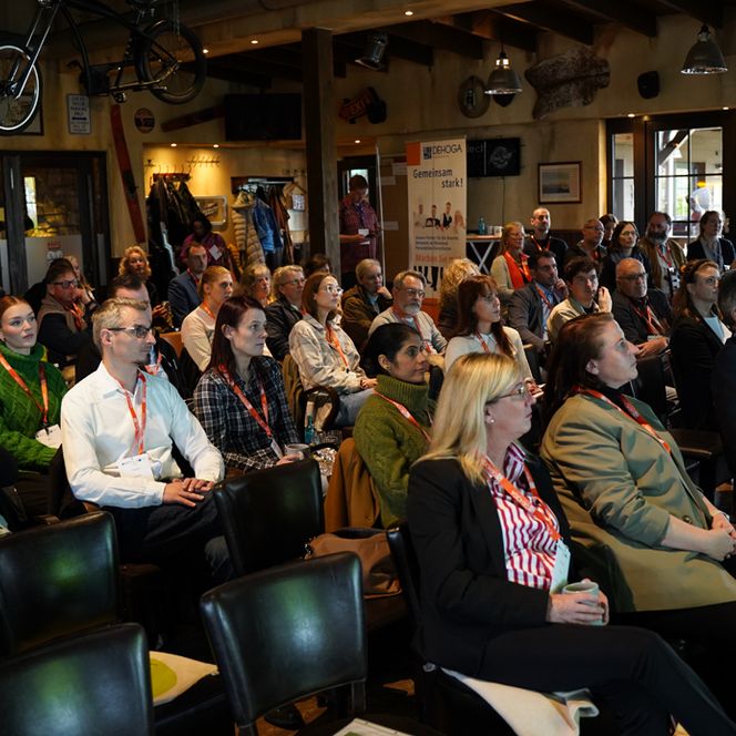 Ein Publikum aus über 50 Personen blickt interessiert nach vorne zur Bühne.