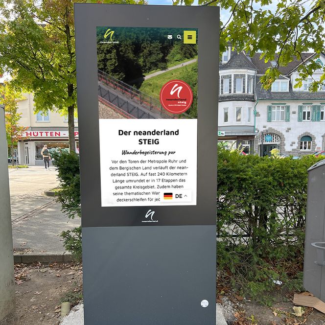 Digitale Infostele in Heiligenhaus mit Infos und dem Siegel vom neanderland STEIG Qualitätsbetrieb Das Bild zeigt eine digitale Infostele, die Informationen zum neanderland abbildet sowie das Siegel des neanderland STEIG Qualitätsnetzwerks.