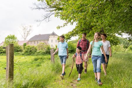 Familie wandert entlang einer umzäunten Wiese vorbei an Haus Bürgel in der Urdenbacher Kämpe nahe Monheim am Rhein