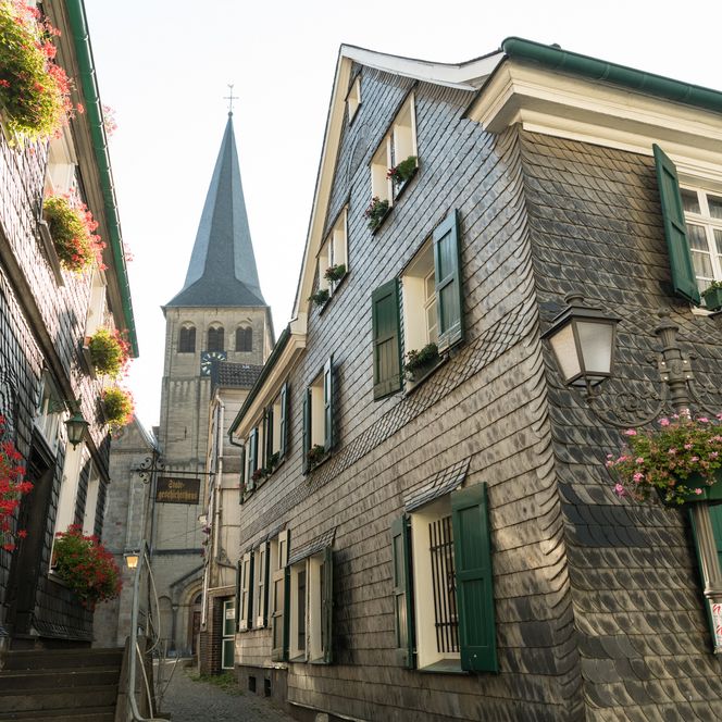 Gasse in der Oberstadt von Mettmann entlang des Schiefergebäudes des Stadtgeschichtshauses zur St. Lambertus Kirche im Hintergrund 