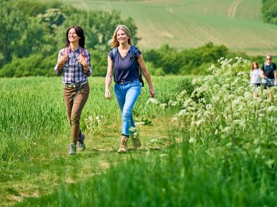 Zwei Freundinnen wandern auf einem bewachsenen Feldweg bei der Eröffnungswanderung der neanderland WANDERWOCHE 2022