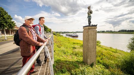 Skulptur Leda von Markus Lüpertz in Monheim am Rhein. Zwei Spaziergänger am Rhein.