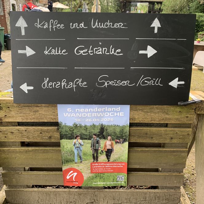 Schilder mit Richtungspfeilen und ein Plakat der neanderland WANDERWOCHE 2026