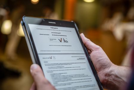 Handen met een tablet met informatie uit een toegankelijkheidsenquête