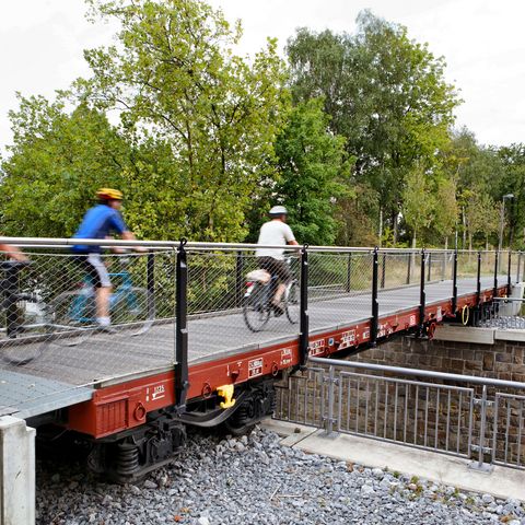 Drei verschwommene Radfahrer auf fokussierte Waggonbrücke auf dem PanoramaRadweg niederbergbahn in Heiligenhaus