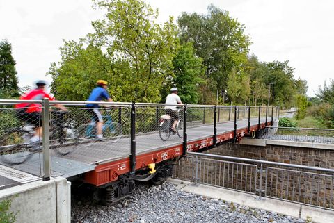 Drei verschwommene Radfahrer auf fokussierte Waggonbrücke auf dem PanoramaRadweg niederbergbahn in Heiligenhaus