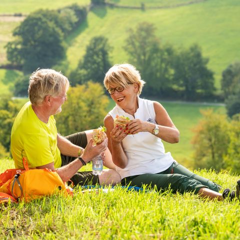 Una mujer y un hombre están haciendo un picnic en un prado en el Neanderland STEIG en Elfringhauser Suiza.