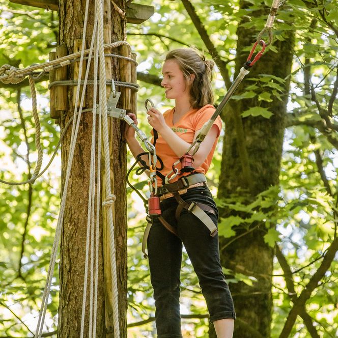 Jugendliche steht auf Plattform oben im Baum im Waldkletterpark Velbert-Langenberg.