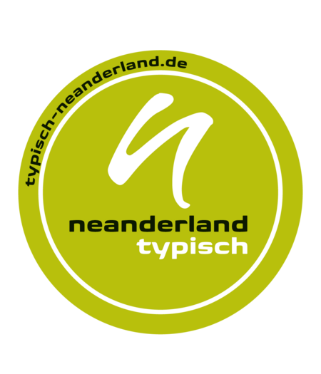 شعار مستدير TYPISCH ختم إنسان نياندرلاند (أبيض صغير n فوق أسود أصغر بحروف "neanderland" مع حروف بيضاء "نموذجية" تحتها في دائرة بيضاء مع نموذج neanderland-de بالخارج على خلفية خضراء)